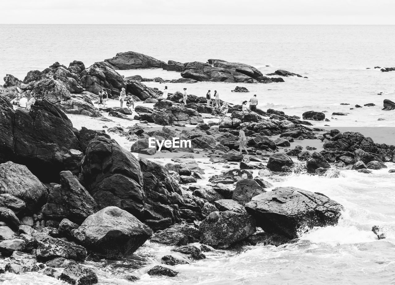 Rocks on beach by sea against clear sky