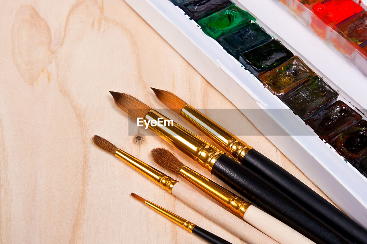 Close-up of paintbrushes and watercolor paints on table