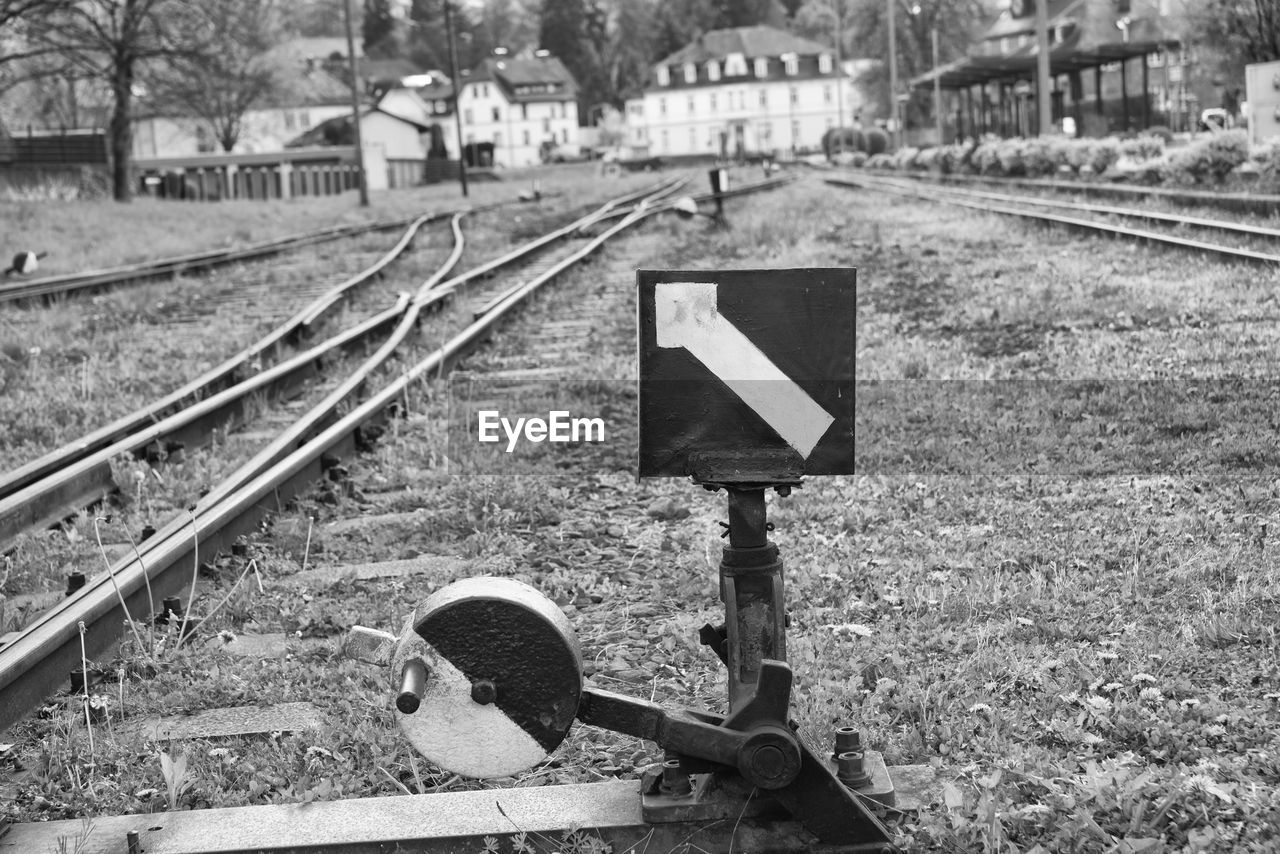 Arrow sign by railroad tracks on field