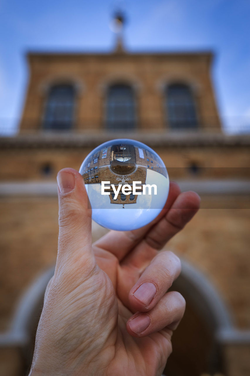 Close-up of human hand holding transparent sphere