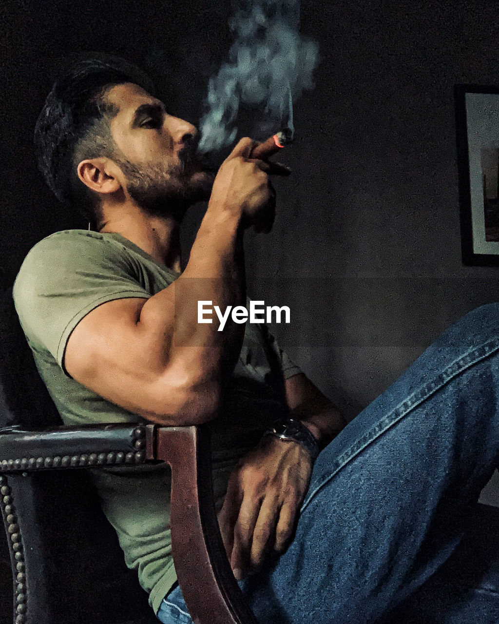 Man smoking cigar while sitting on chair