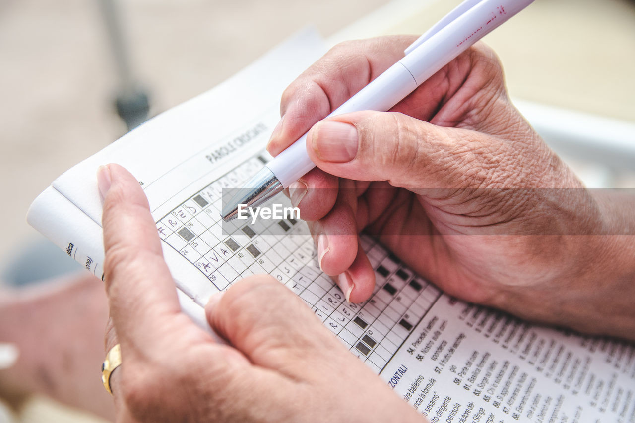 Cropped hands solving puzzle on newspaper