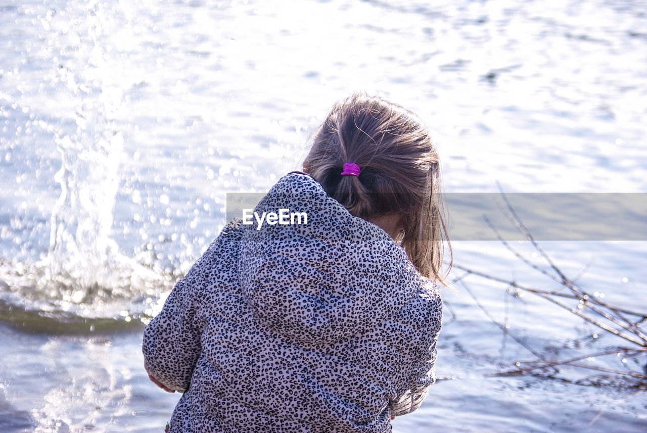 Rear view of girl playing with water on sunny day