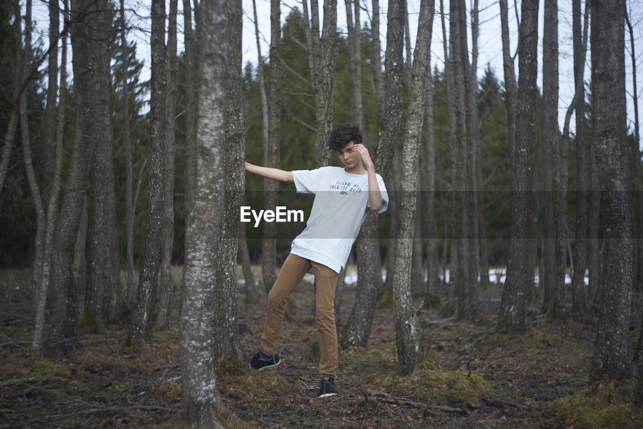 Portrait of man standing against trees in forest