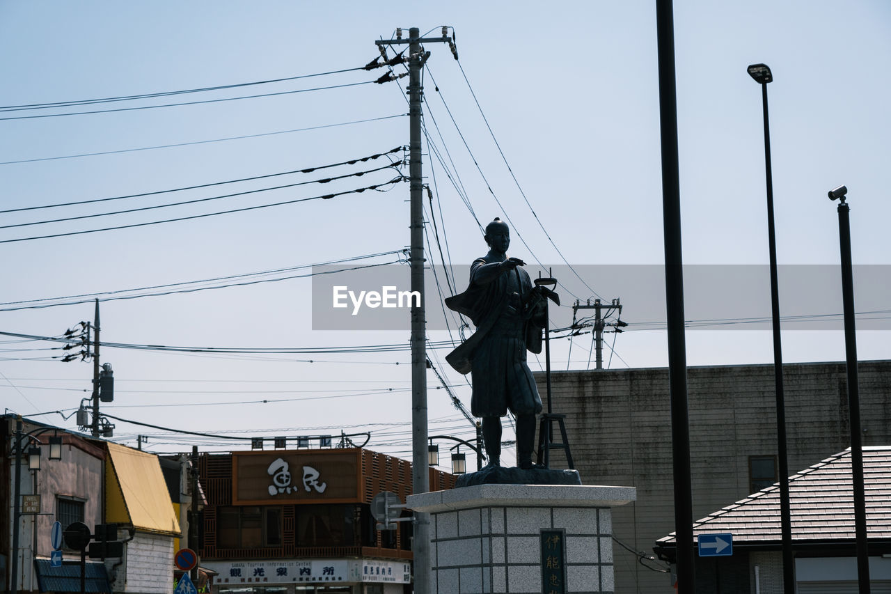 LOW ANGLE VIEW OF STATUE ON ELECTRICITY PYLON AGAINST SKY