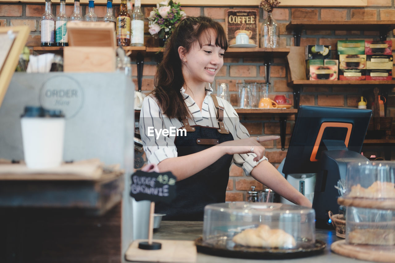 Barista smiling while using computer in cafe