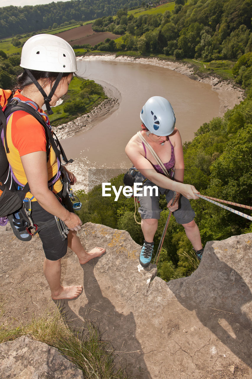 Friend supervising her friend as she descendes steep cliff in wales