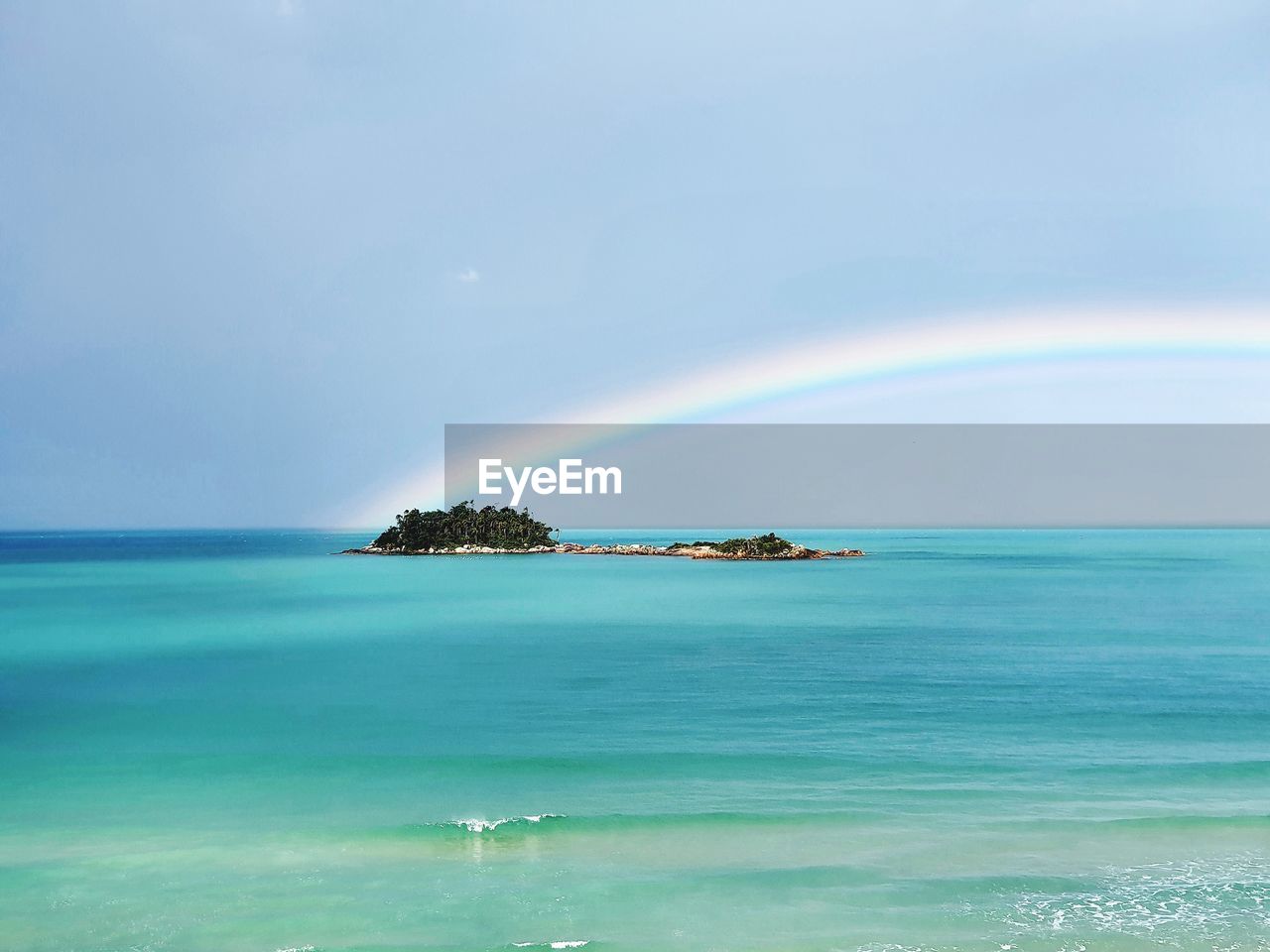 Scenic view of sea against rainbow in sky