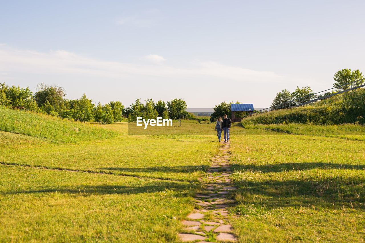 REAR VIEW OF PERSON WALKING ON FIELD