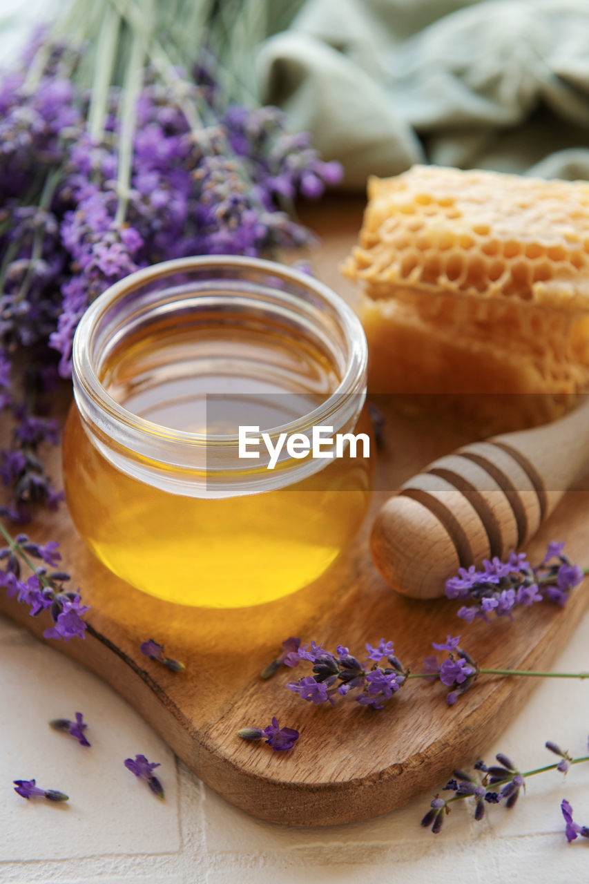 Glass of honey, honeycomb and lavender flowers