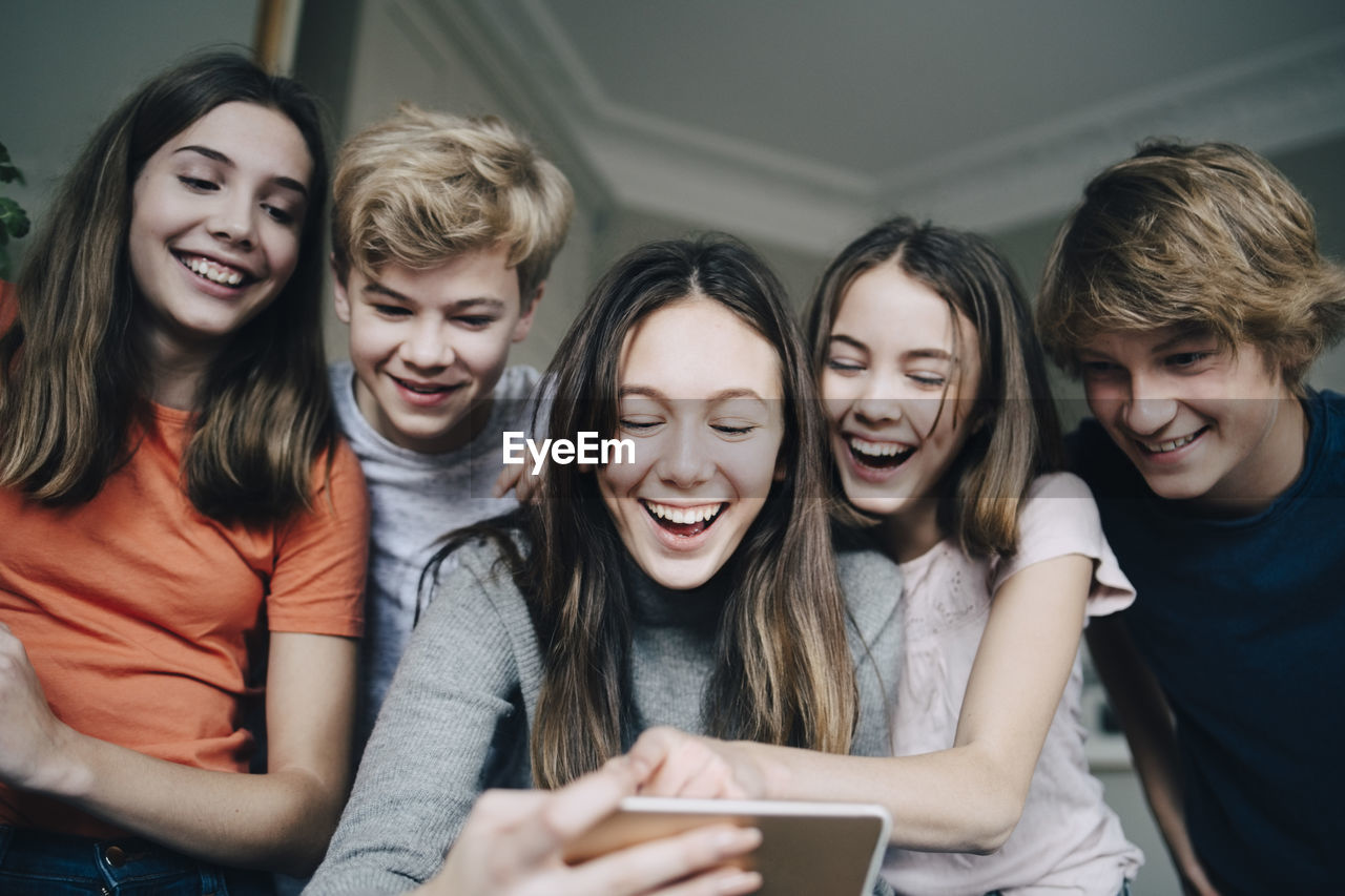 Happy male and female friends taking selfie through smart phone at home