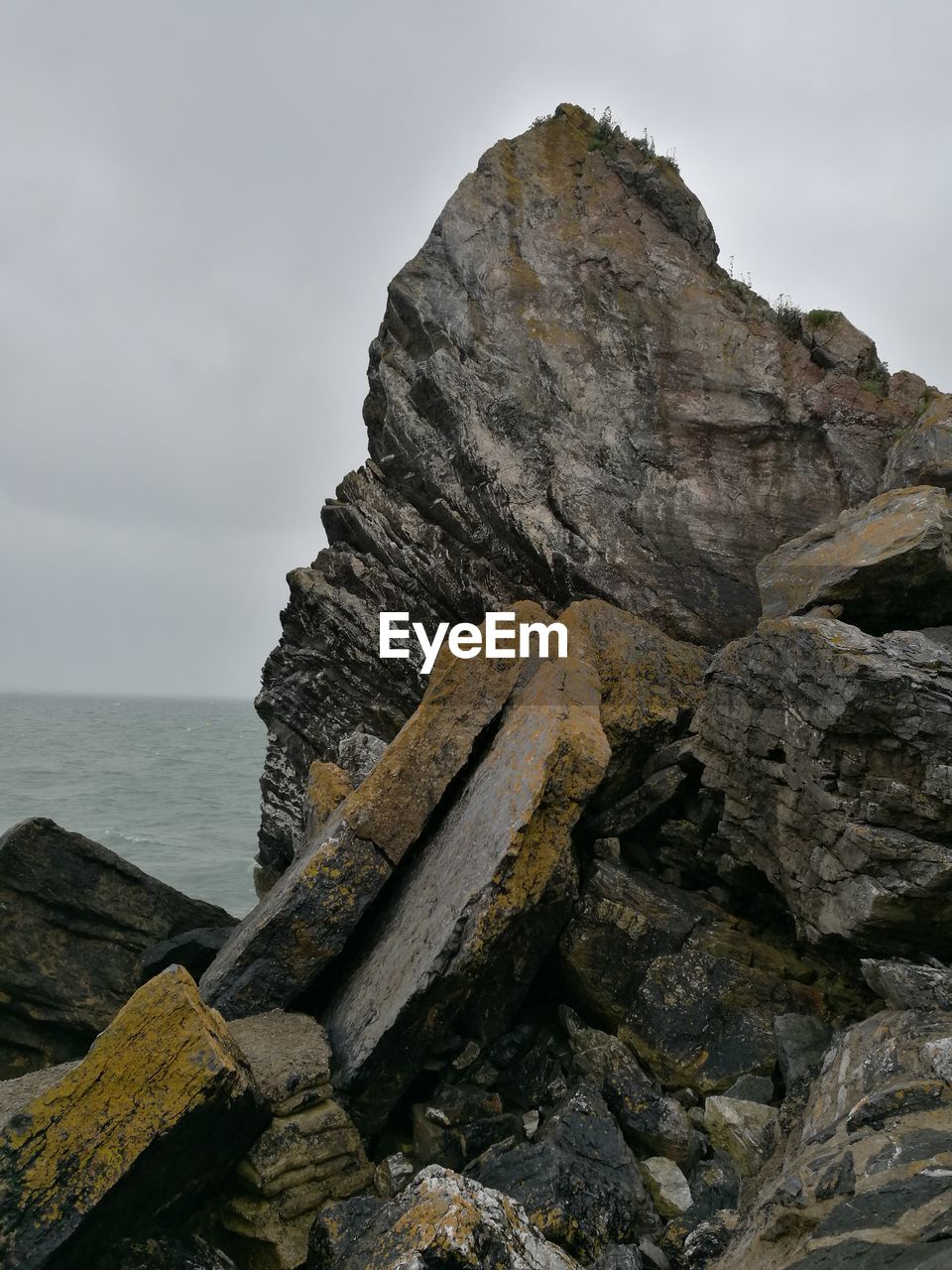 CLOSE-UP OF ROCK FORMATIONS IN SEA AGAINST SKY