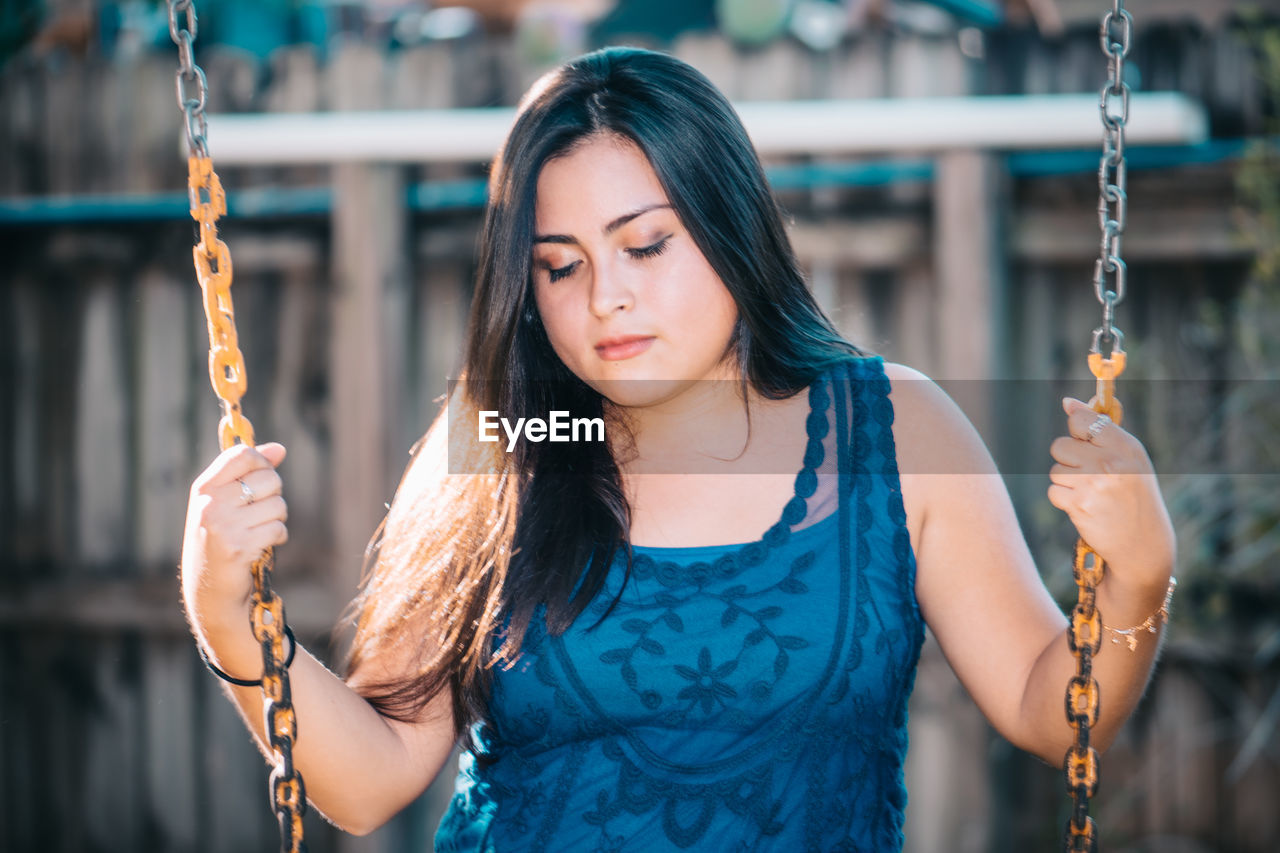 Close-up of young woman holding swing chain in playground