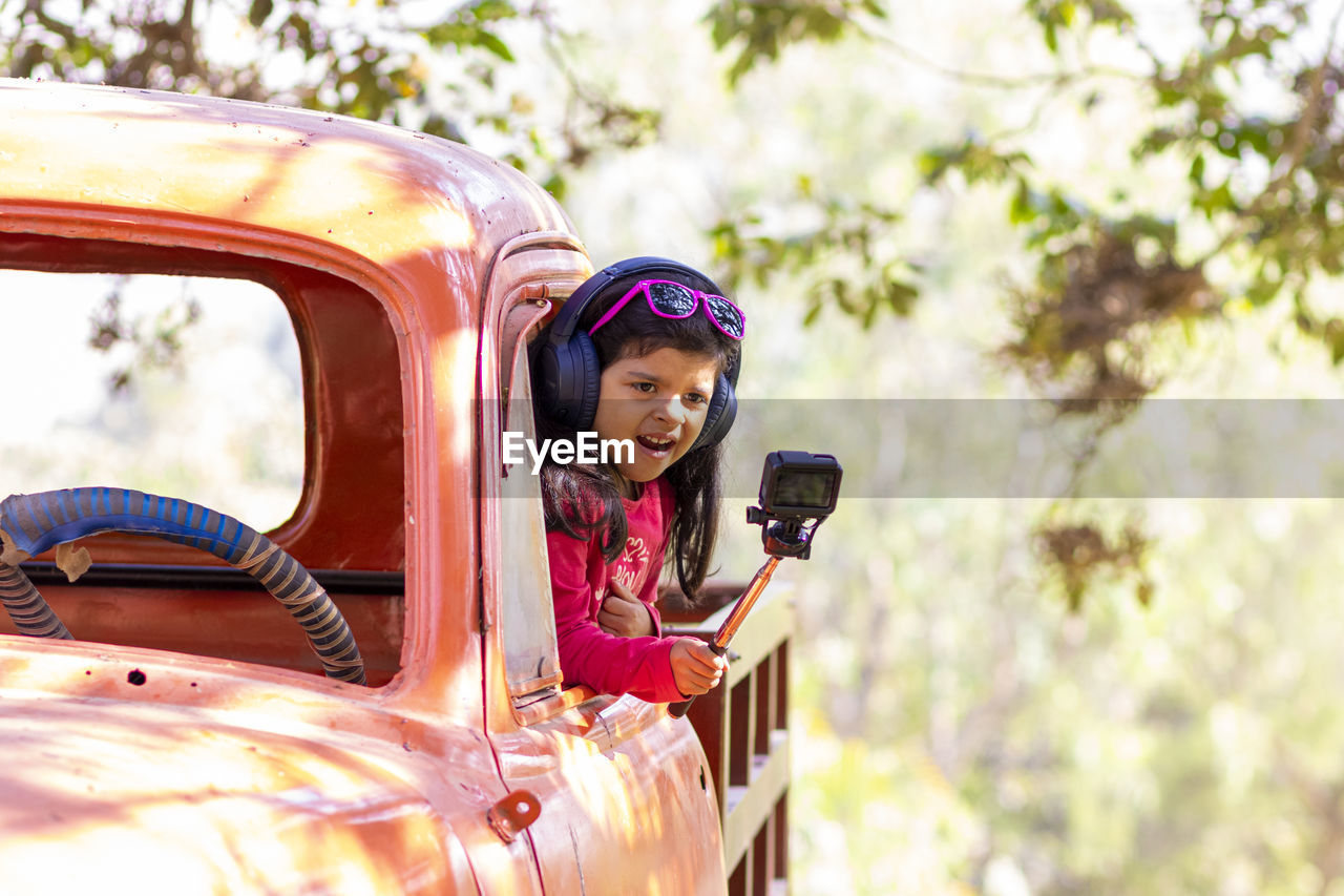 Smiling girl holding camera in car 