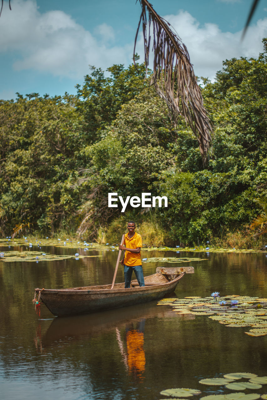 Scenic view of a man standing in a boat in a river