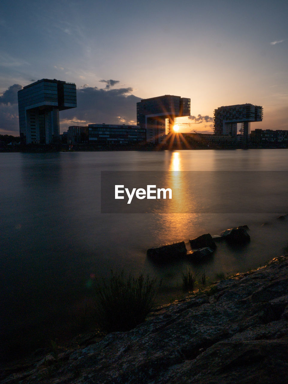 BUILDINGS BY SEA AGAINST SKY AT SUNSET