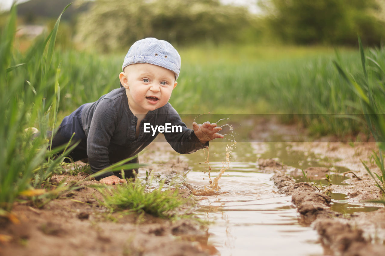 FULL LENGTH OF CUTE BOY ON GRASS AT FIELD