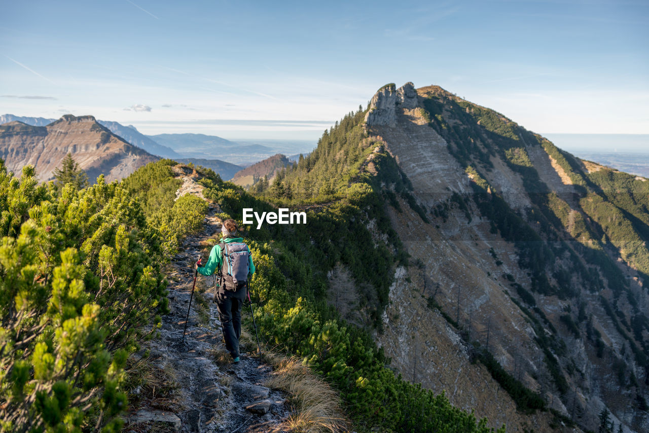 Woman hiking on footpath in alpine landscape in autumn, osterhorn mountain range, salzburg, austria