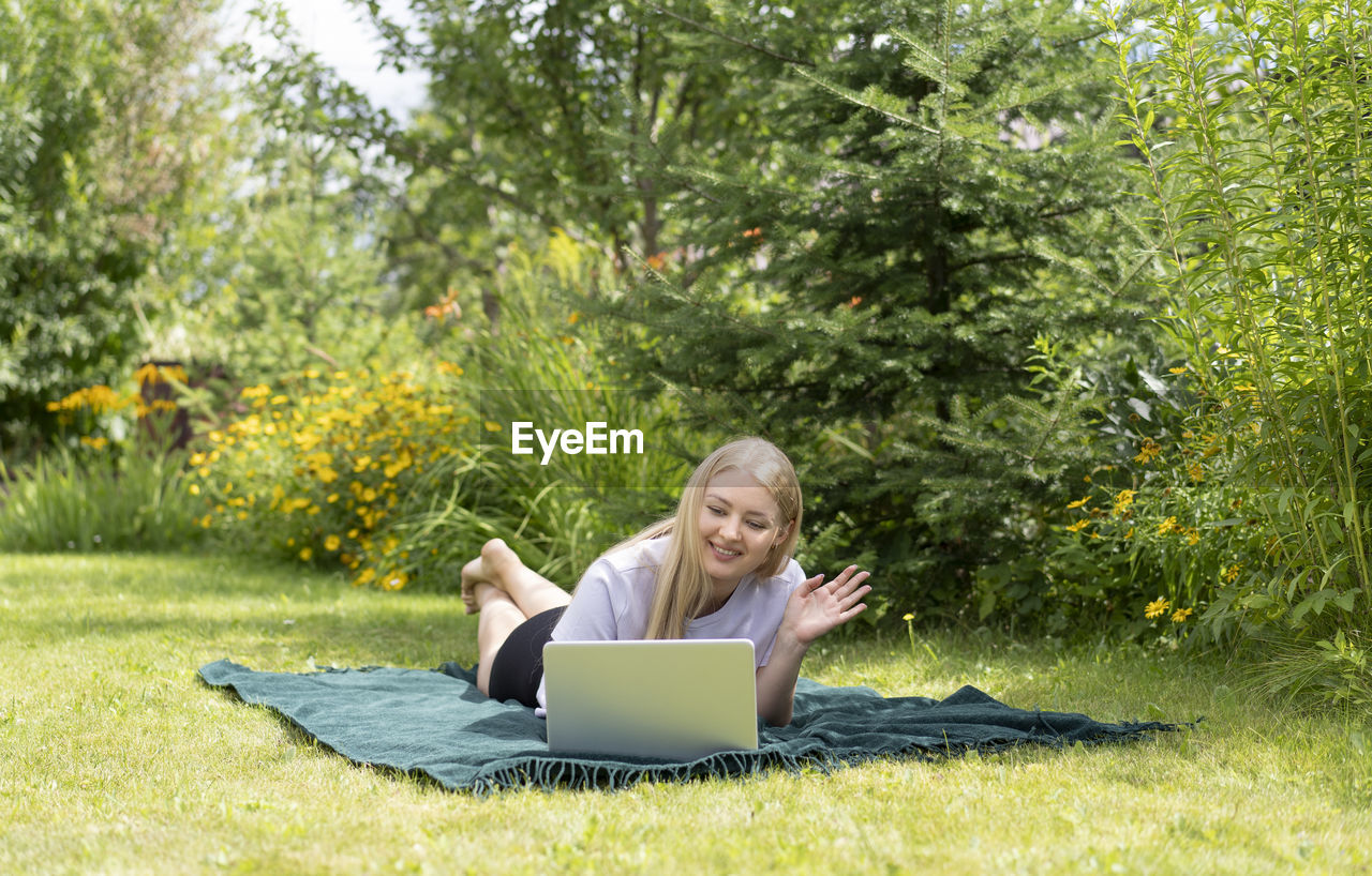 portrait of woman using laptop while sitting on field