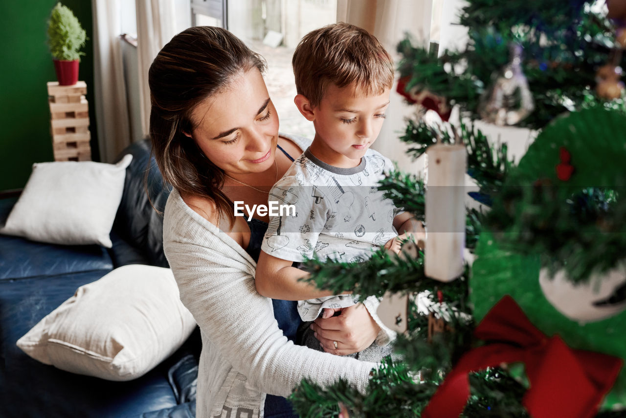 Mother helping son in decorating christmas tree