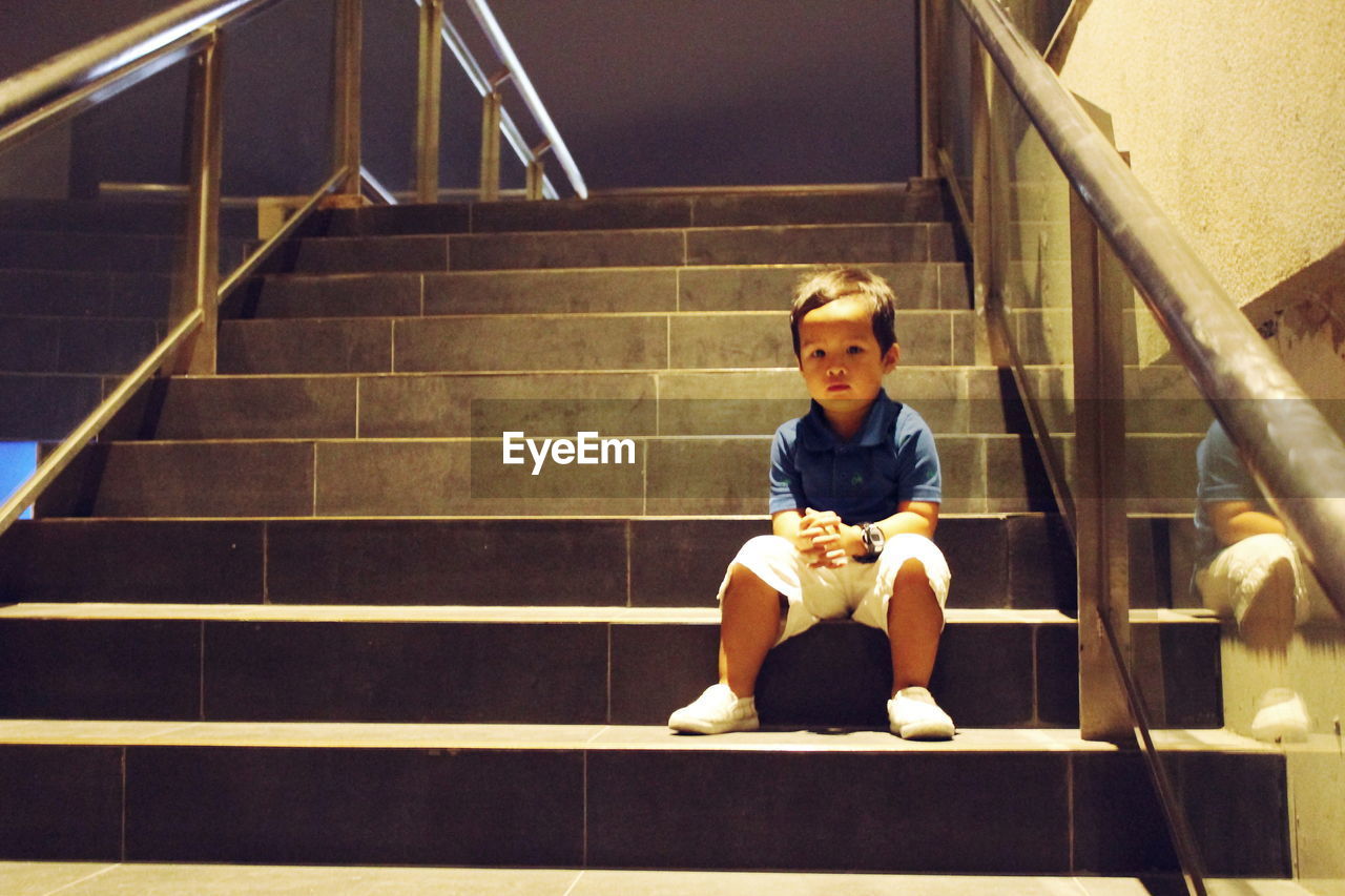 FULL LENGTH PORTRAIT OF BOY SITTING ON STEPS