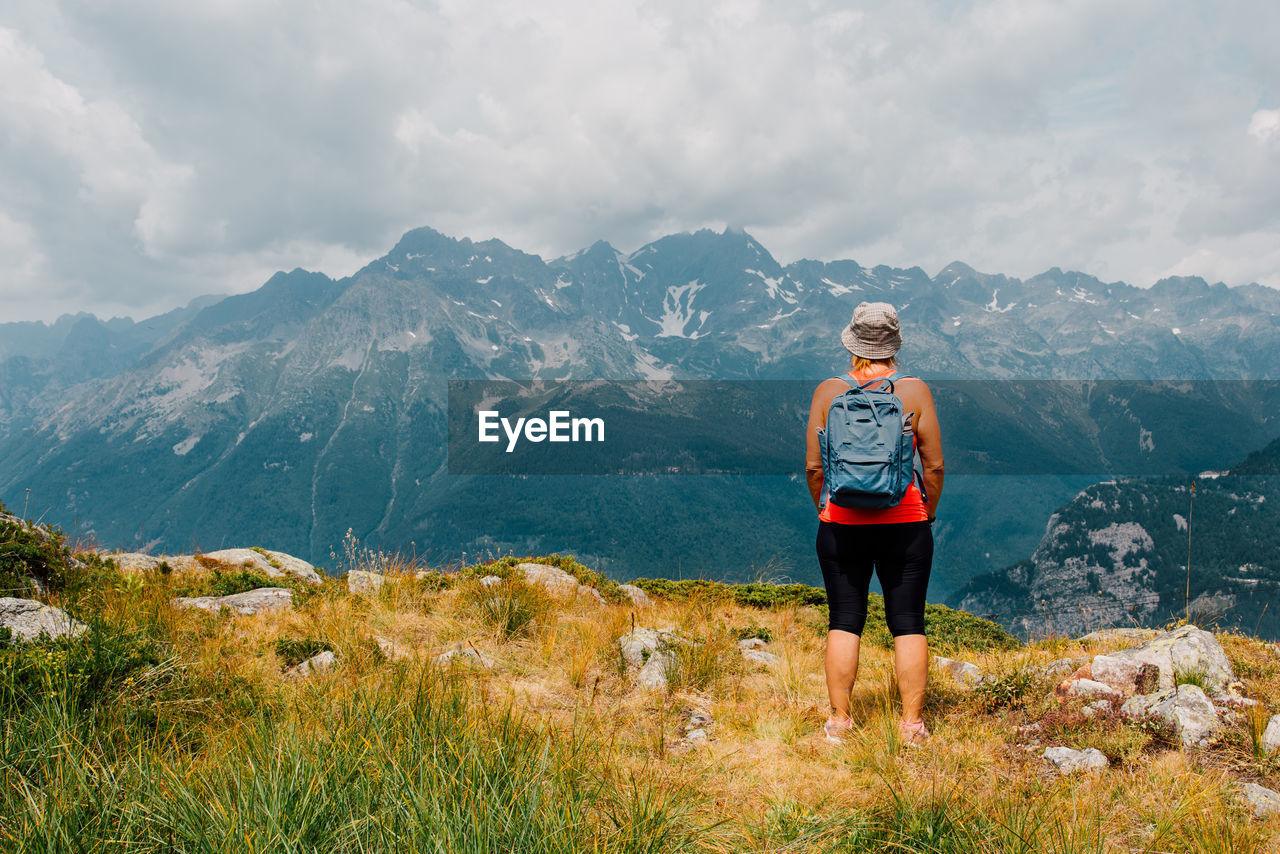 Rear view of woman standing against mountain and sky