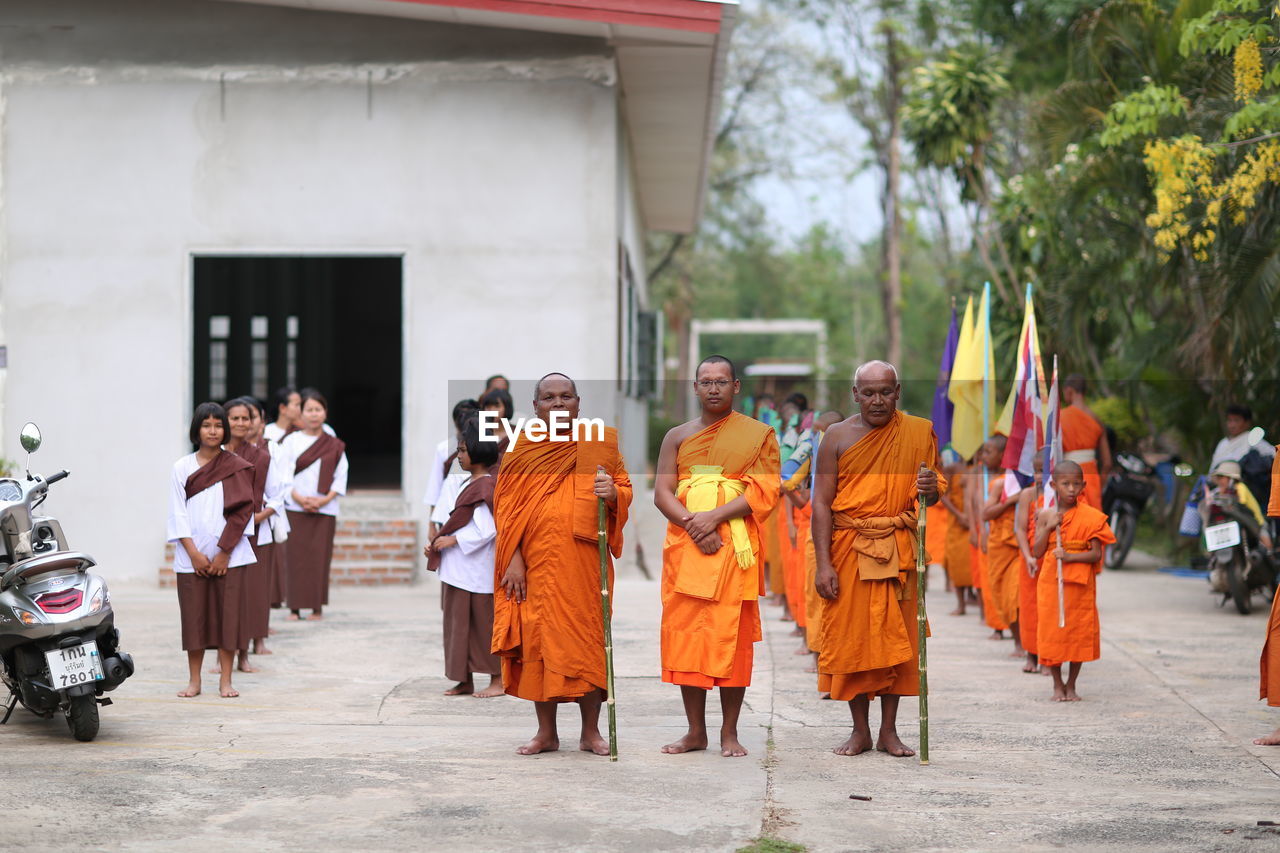 PEOPLE STANDING ON STREET AGAINST BUILDING