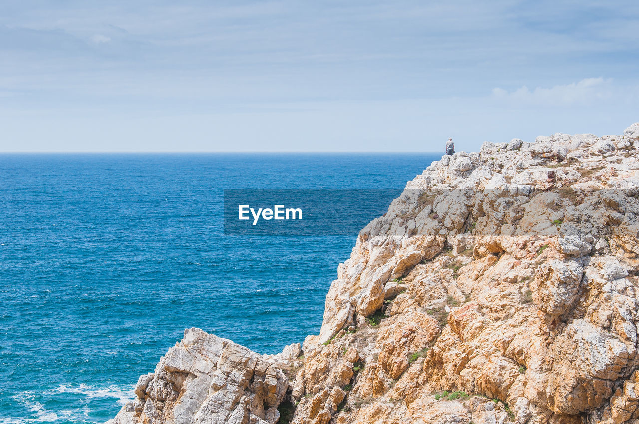 ROCK FORMATIONS BY SEA AGAINST BLUE SKY