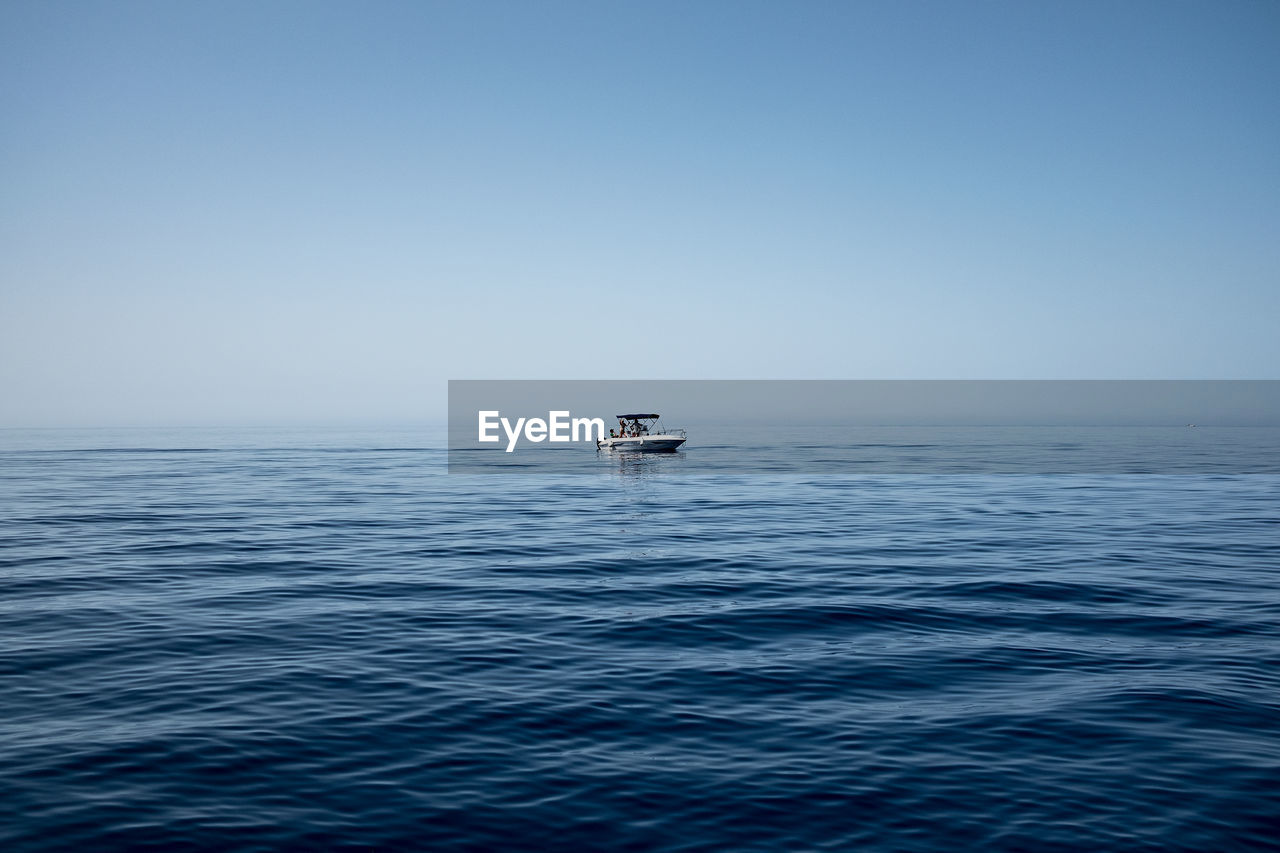 Boat sailing in sea against clear sky