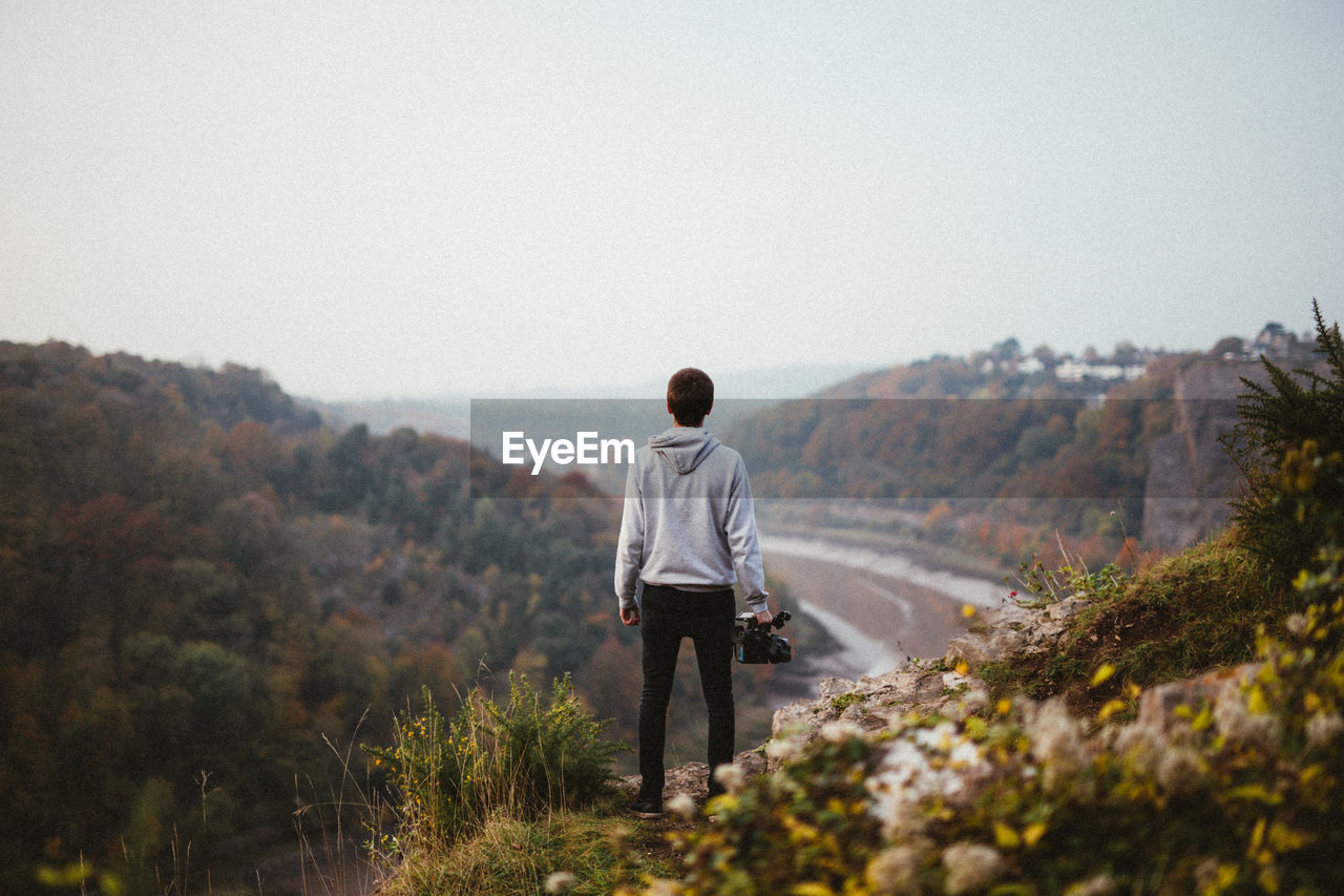 Rear view of man standing on mountain in forest