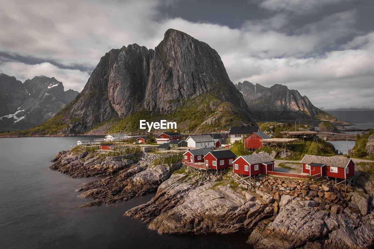 Houses on rock formation by sea against sky