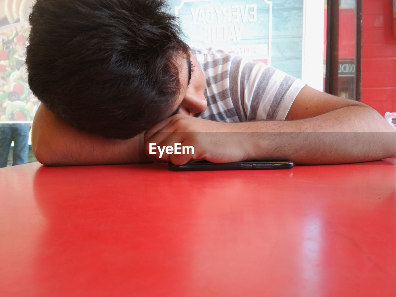 Close-up of teenage boy leaning on red table