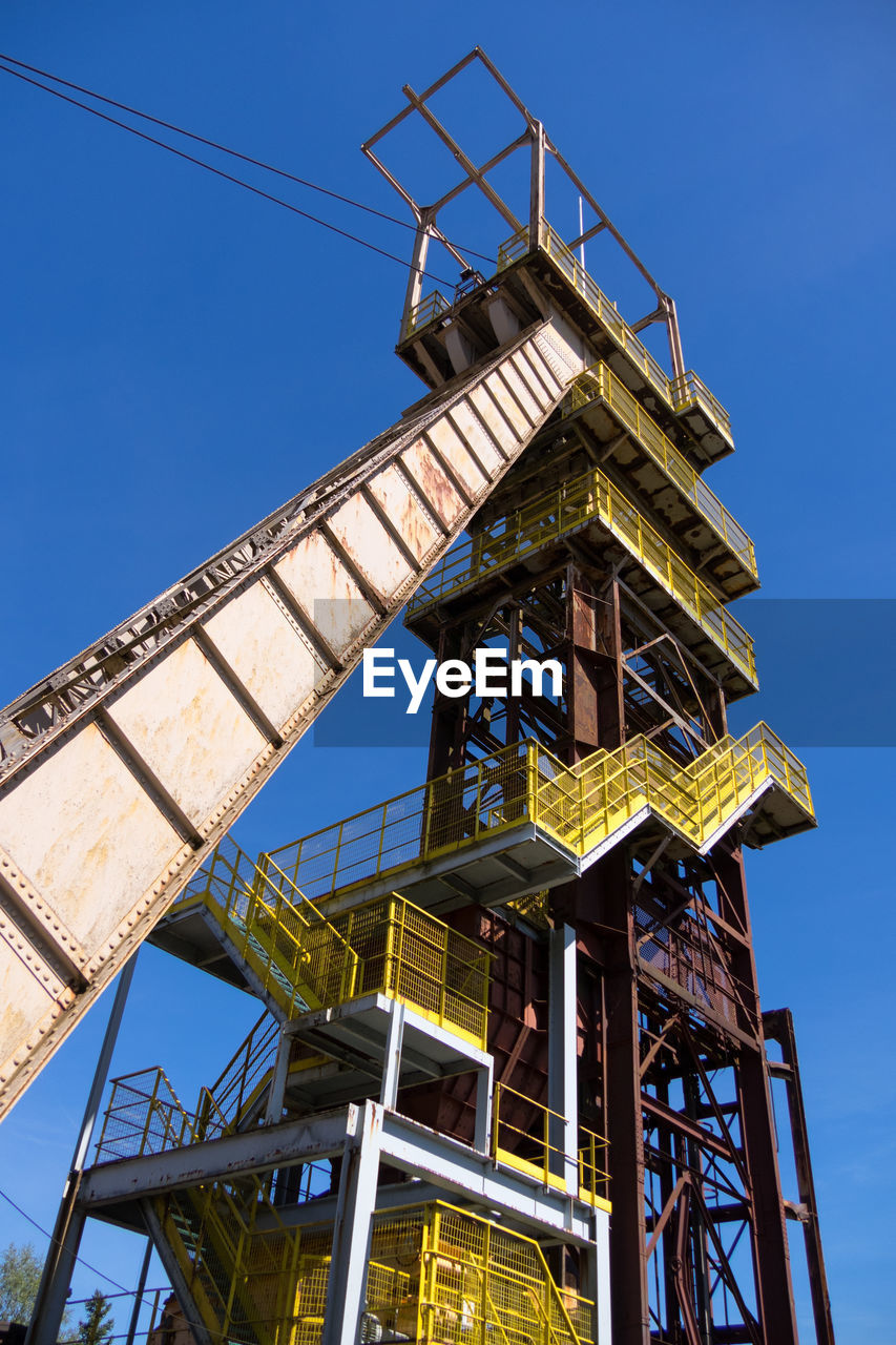 LOW ANGLE VIEW OF CRANE AT CONSTRUCTION SITE AGAINST CLEAR SKY