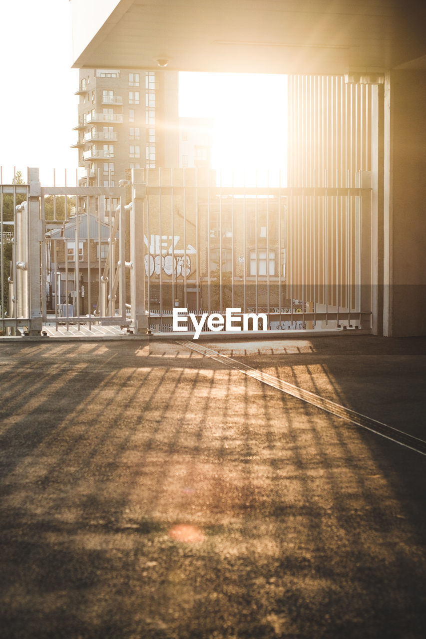 Empty street amidst buildings against sky during sunset