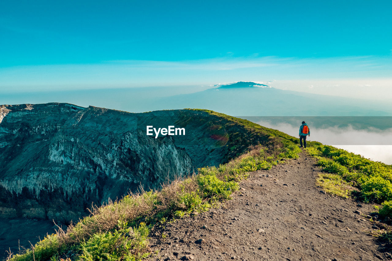 Scenic view of a hiker at volcanic crater - the ash pit on mount ol doinyo lengai in tanzania