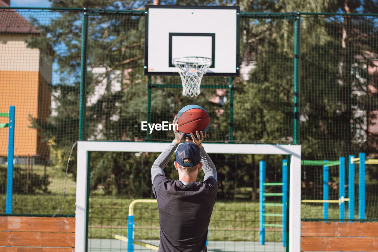 Blond boy in sportswear practices shooting a basketball from behind the three-point line. basketball