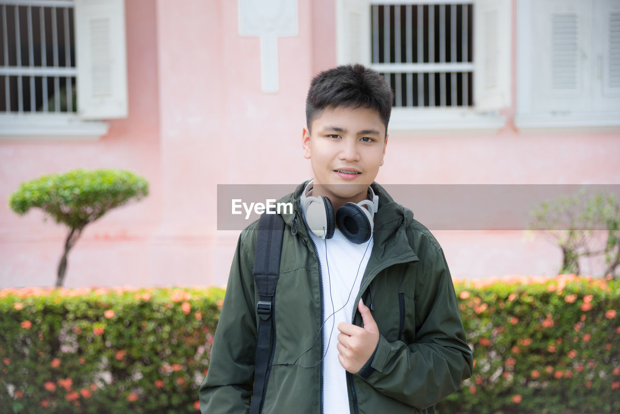 Portrait of smiling boy standing against building