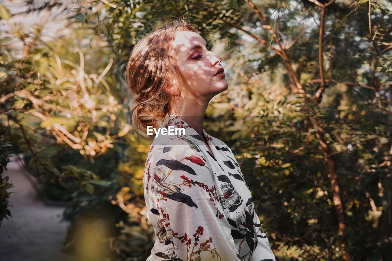 Side view of woman standing against plants in park