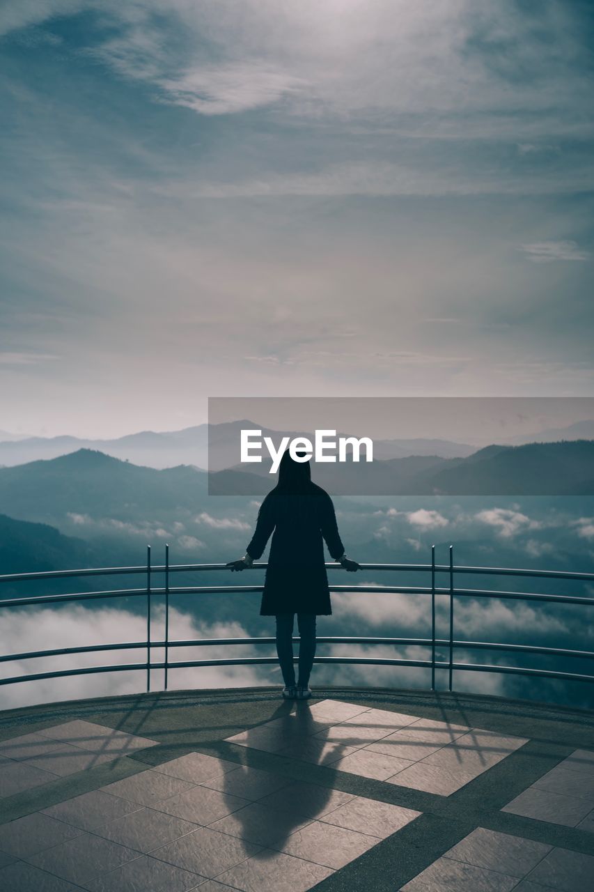 Rear view of woman looking at mountains against sky