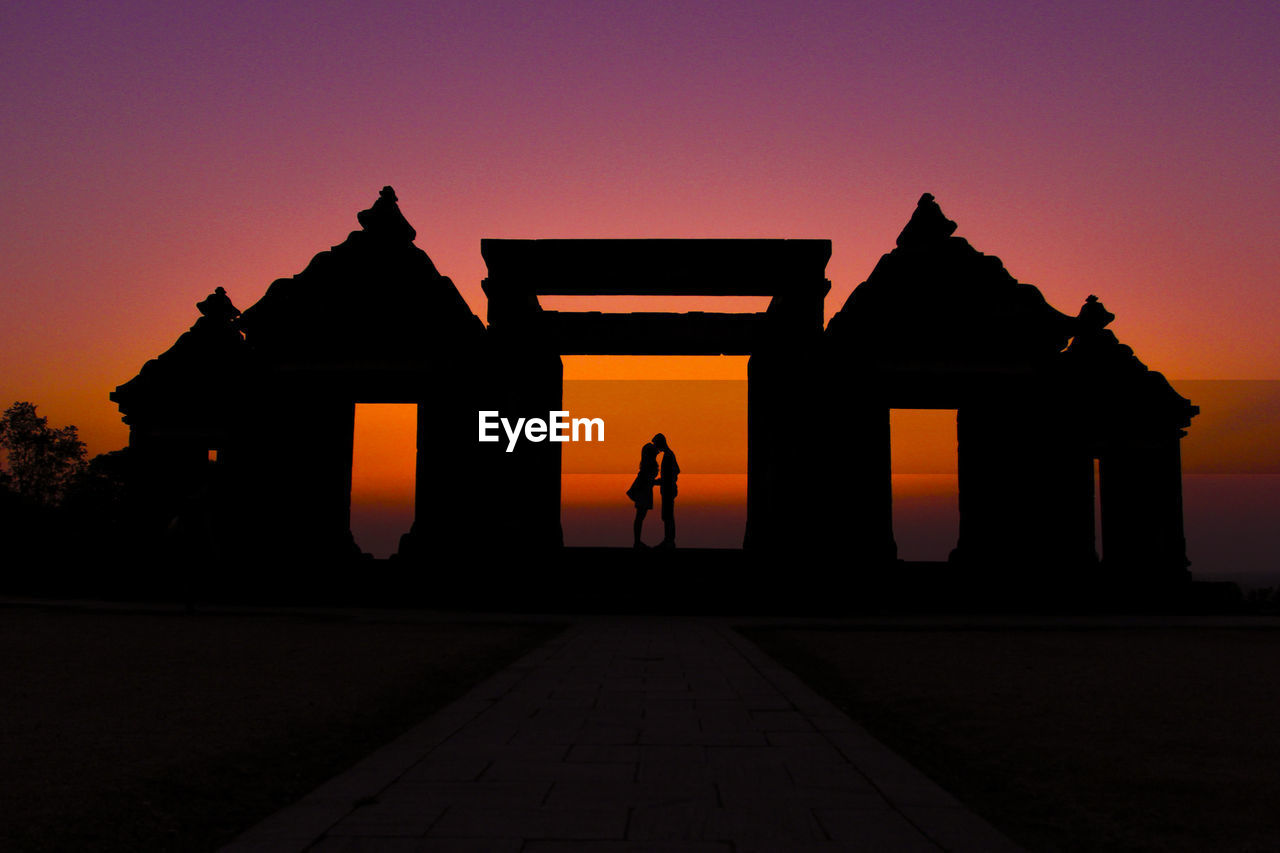 Silhouette couple kissing on gateway of ratu boko ruins against clear sky
