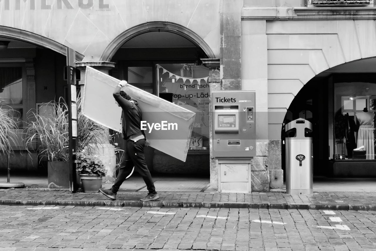 WOMAN WALKING ON FOOTPATH IN STREET