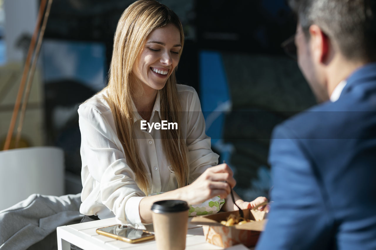 Businesswoman having lunch with colleague in cafeteria at office