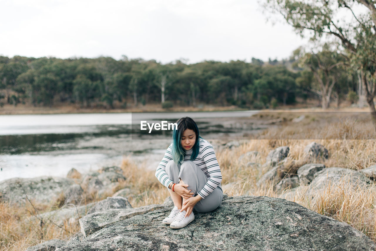 Thoughtful young woman sitting on rock