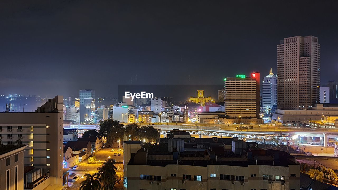 Illuminated buildings in city against sky at night