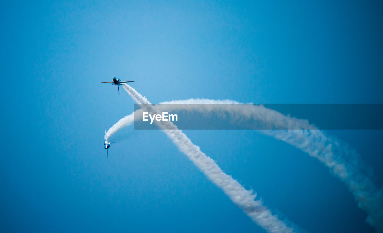 Low angle view of airplane flying against blue sky