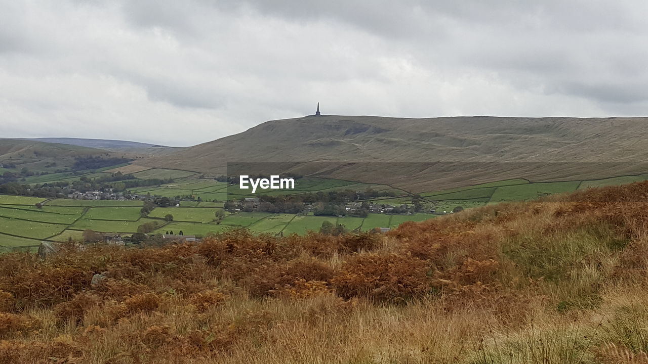 SCENIC SHOT OF COUNTRYSIDE LANDSCAPE AGAINST CLOUDY SKY