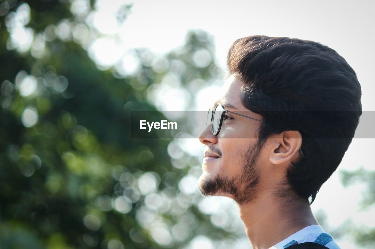 Profile view of young man standing outdoors