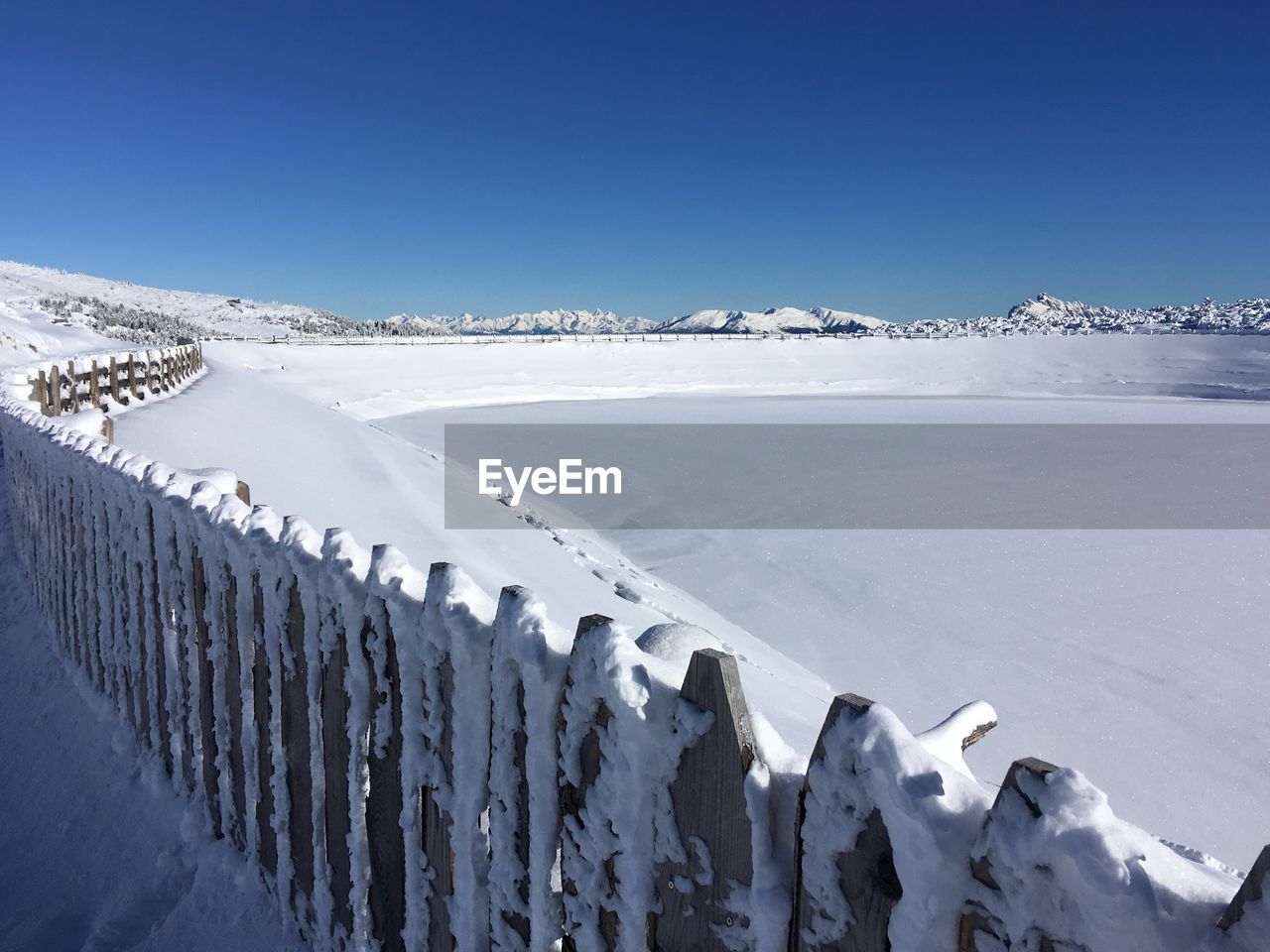 Panoramic view of snow covered landscape against clear blue sky