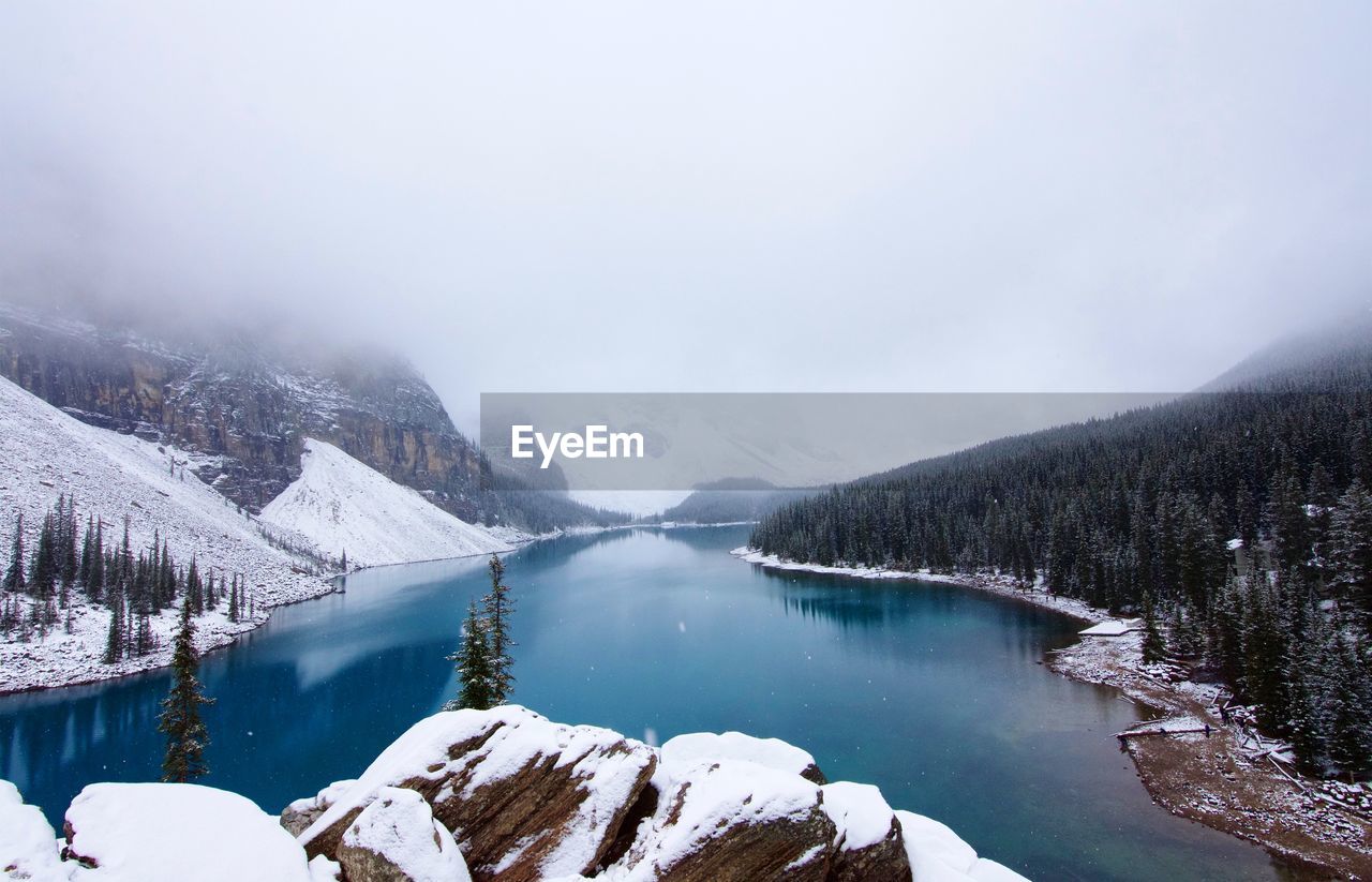 Scenic view of lake by snowcapped mountains against sky