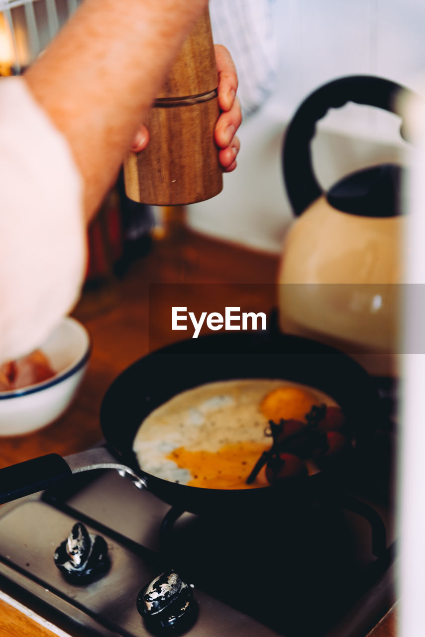 Cropped image hand preparing omelet in kitchen